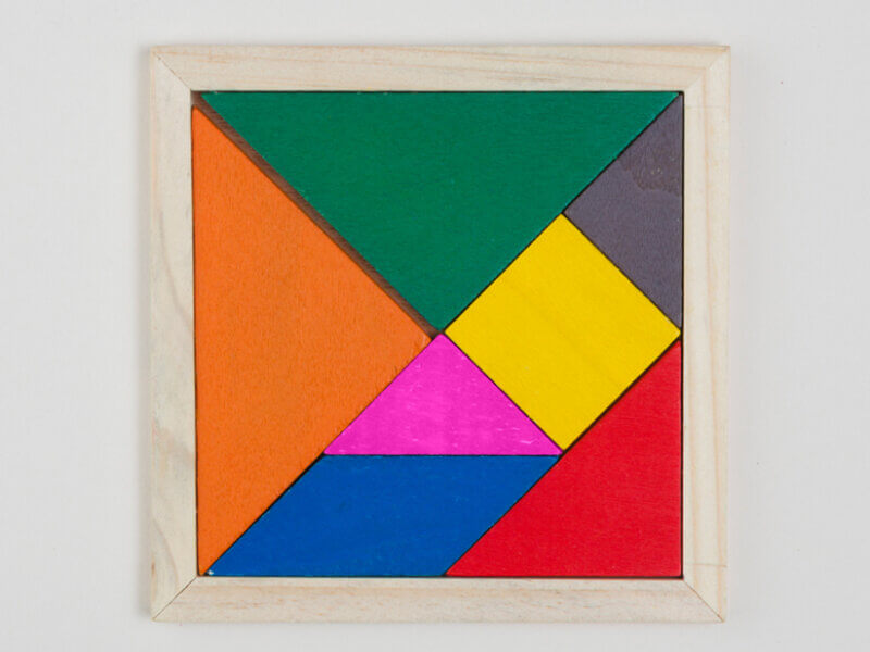 Un tangram visto dall'alto, con le sette forme geometriche (cinque triangoli, un quadrato e un parallelogramma)
